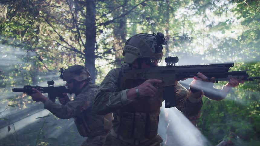 Three soldiers in a forest with their guns raised look around