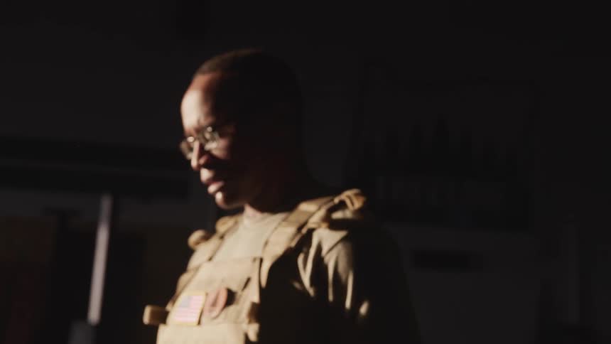 Black man wearing glasses and in a military uniform moves back and forth