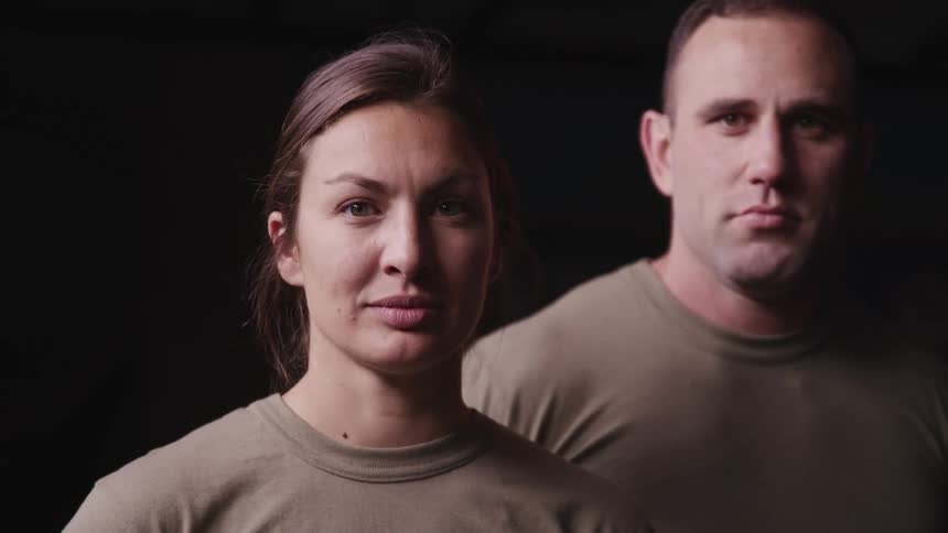 White man and white woman staring at the camera inside a dark room