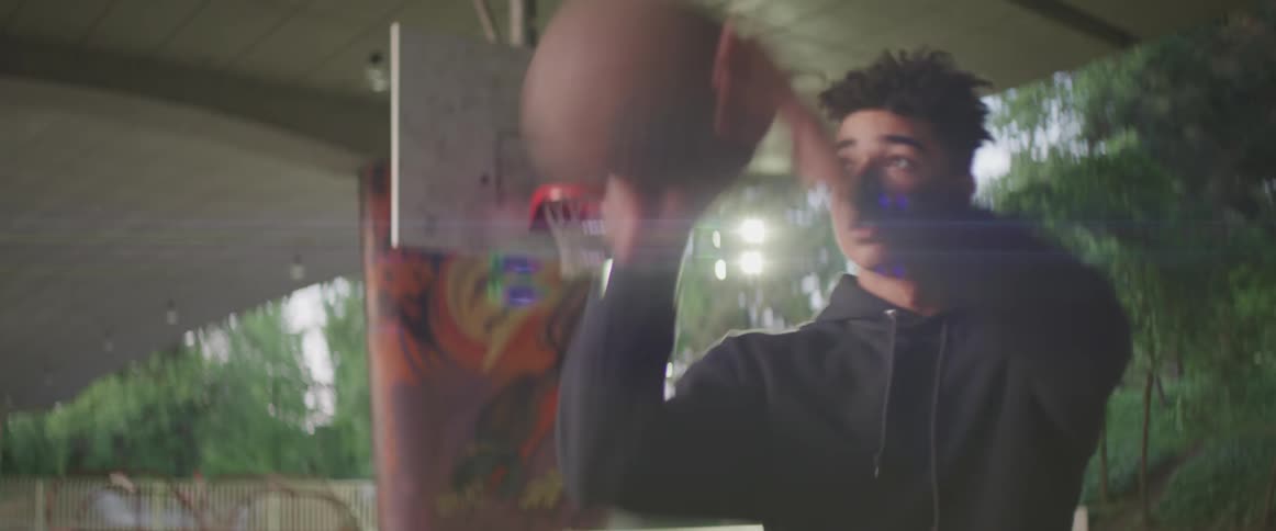 A young man shoots a basketball on an outdoor basketball court during the day