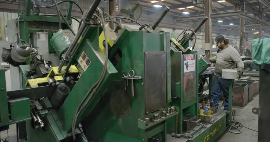 A worker operating machinery in a factory inside a warehouse