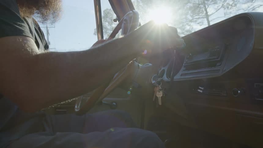 A man puts his car in to drive and starts driving
