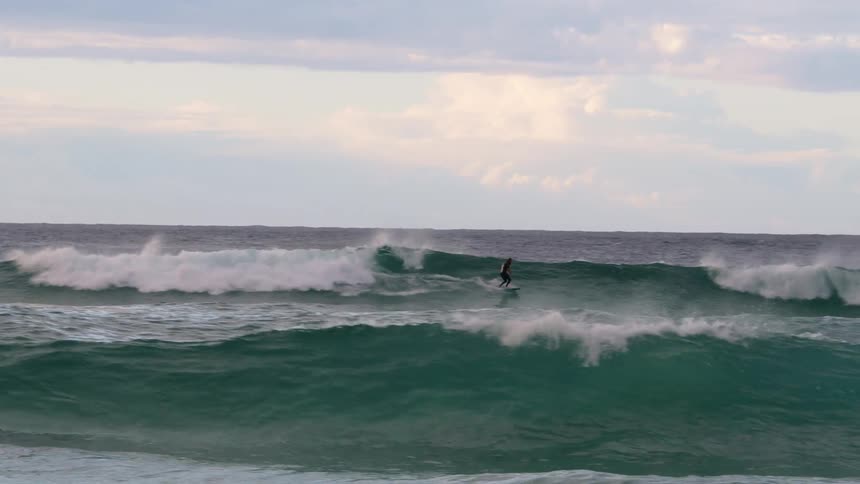 Surfer riding a huge wave on a cloudy day
