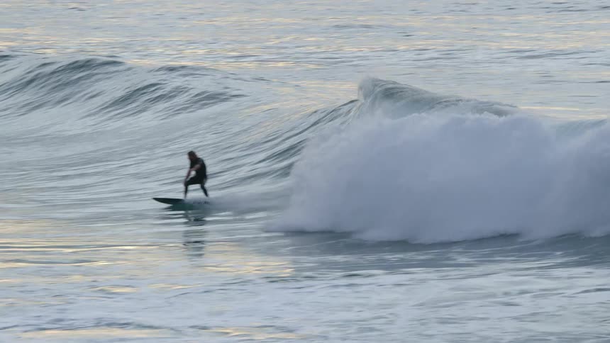 Surfer rides a huge wave as water splashes behind him