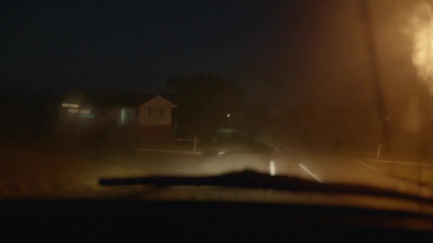 The car drives down the dark road at night