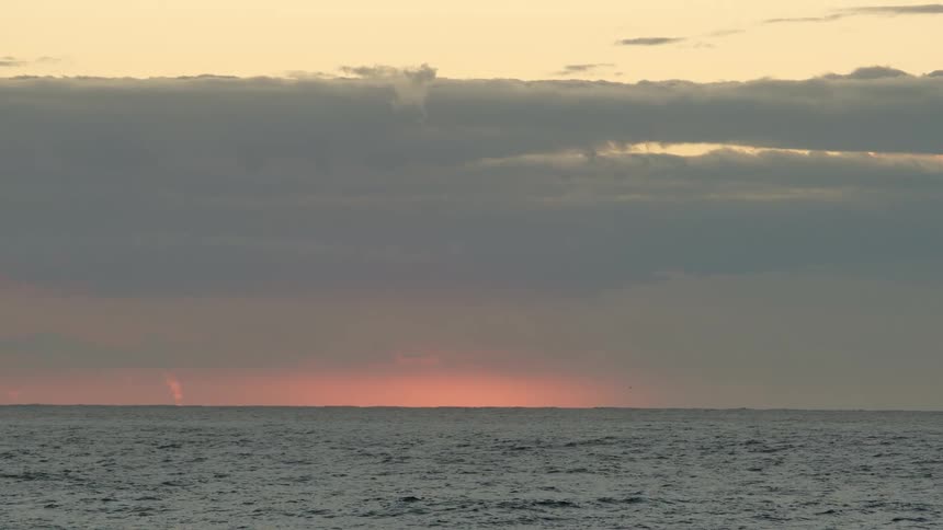 Colorful cloudy sky as waves ripple across the ocean