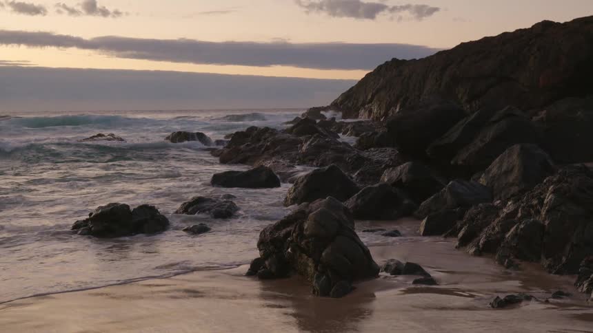 Waves rolling on on rocky coast and over beach