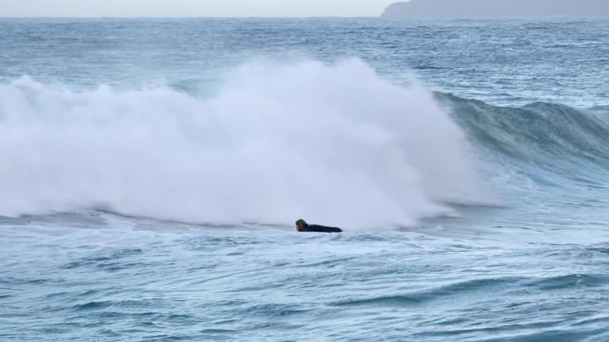 A man swimming in an ocean wave