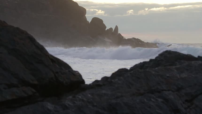 Waves rolling in splashing against rocky coast