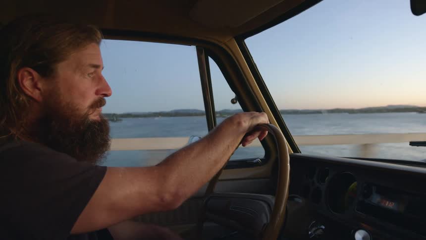 A man speeds down a highway that runs alongside the ocean