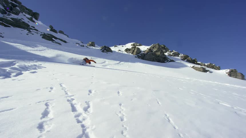A person skiing down a mountain falls down and gets back up and continues skiing