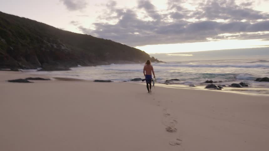 A man carries his surfboard to the water