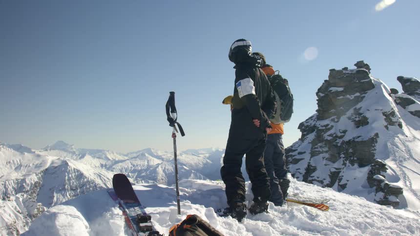 Two people contemplating the mountain landscape from the summit of a mountain