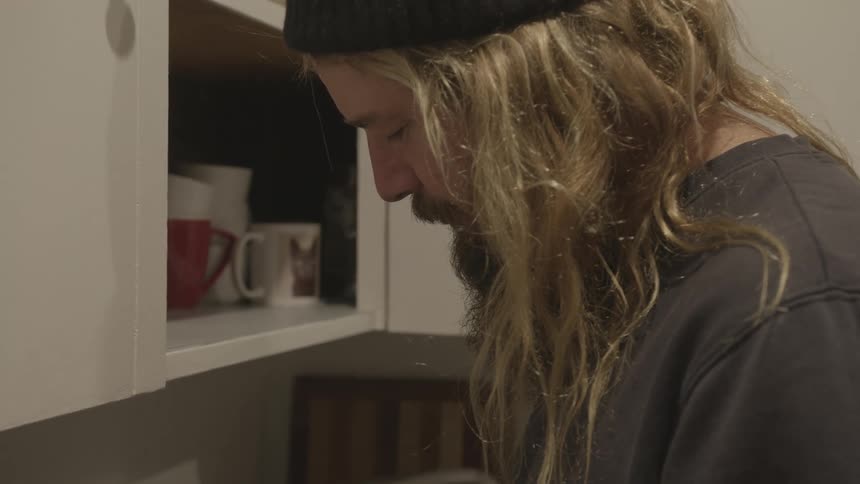 A man with a hat standing in a kitchen with smoke
