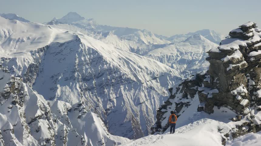 A hiker stopping to enjoy the view in snowy mountains in the wilderness