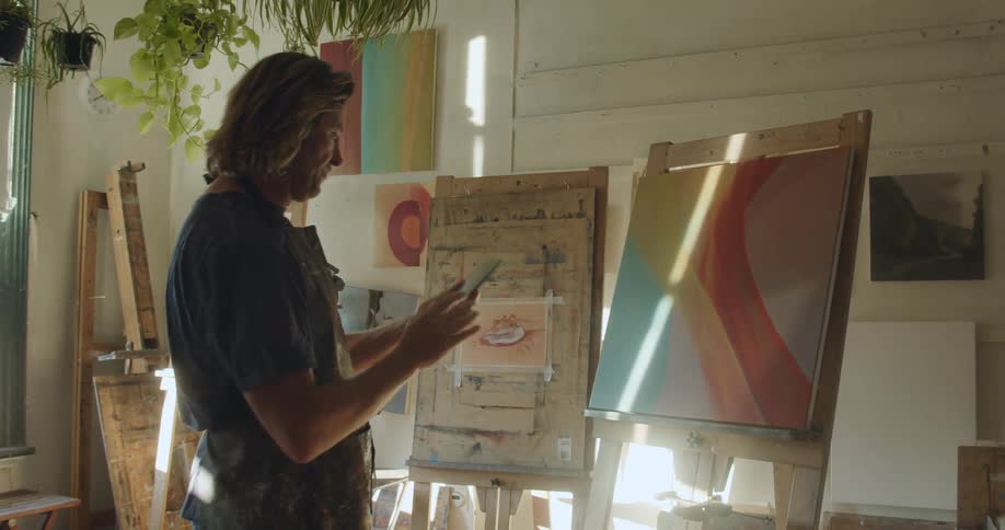 Man takes a photo of a painted canvas with a smart phone
