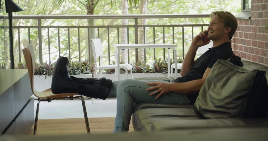 A man is talking on the phone while sitting outdoors