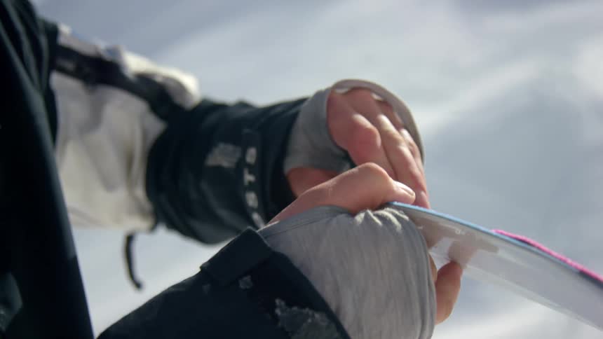 A person peeling the plastic cover of a ski over the snow in the mountain