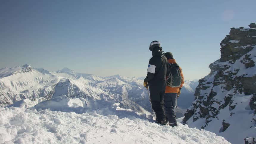 Two skiers standing on the snow covered slopes of a mountain range