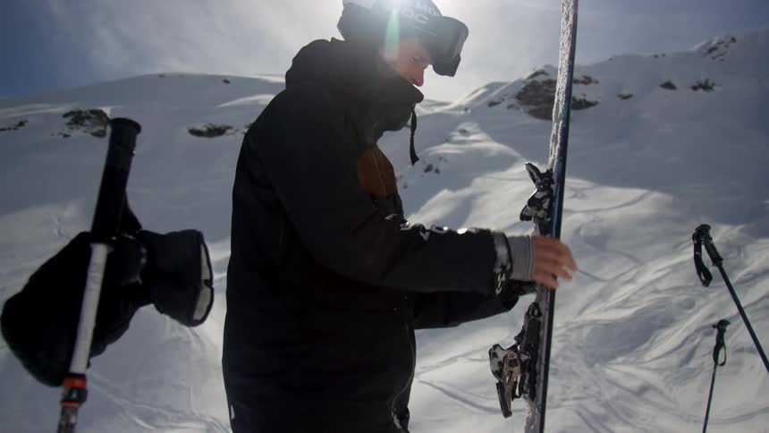 Skier prepares gear to ski on the snow covered mountains