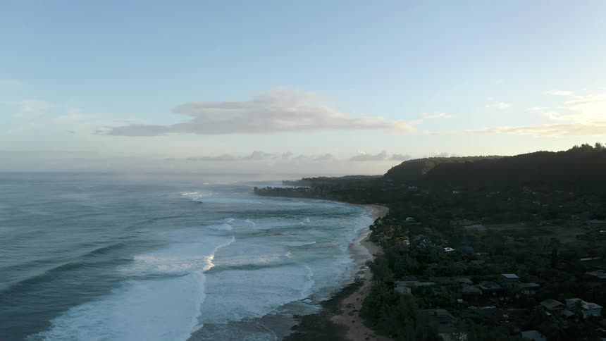 Aerial of gentle waves lapping shoreline on a beach front bay