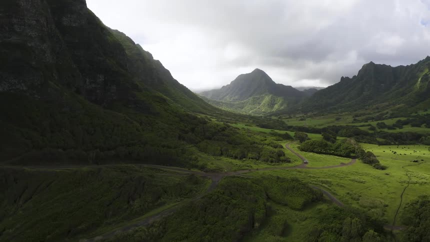 Aerial view of cyclist riding down dirt road through valley on a cloudy day