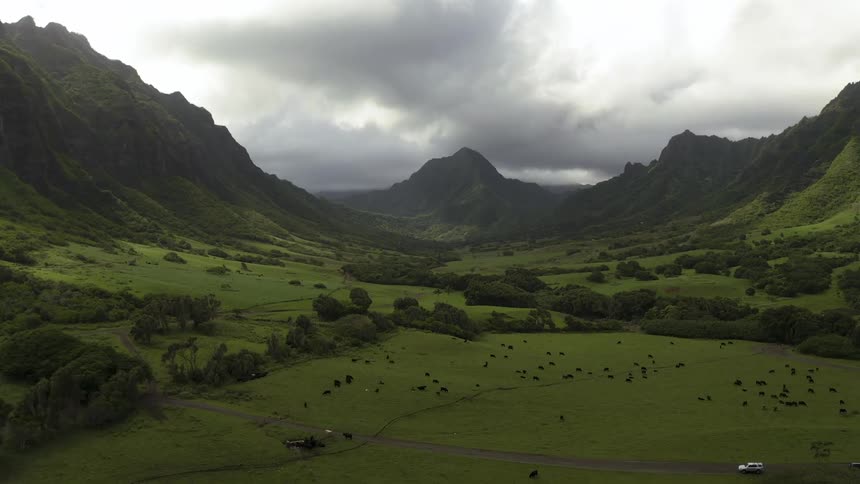Dark clouds hang over the green field and mountains