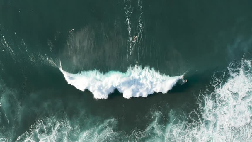An aerial view shooting down of a surfer on a wave crashing in the ocean