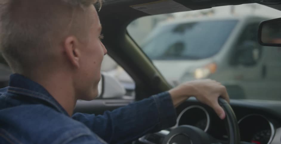 Young man driving a convertible car on the streets of a small town