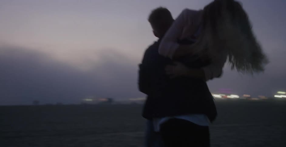 Man picking up his girlfriend at the beach and spinning around