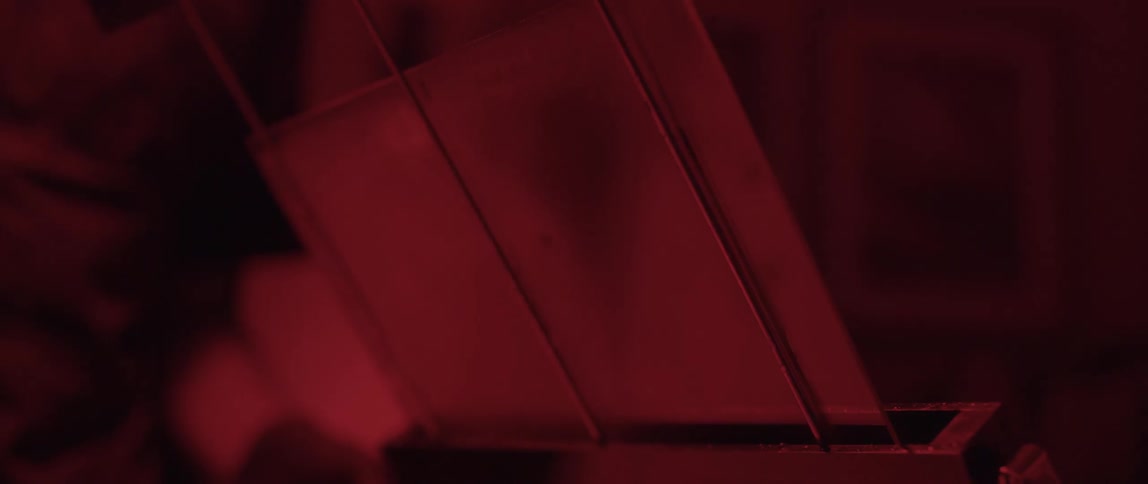 A person with gloves placing glass in a slot in a dark room
