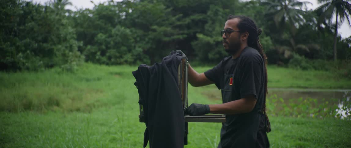 Man inserts plate in old style camera standing in field near pond