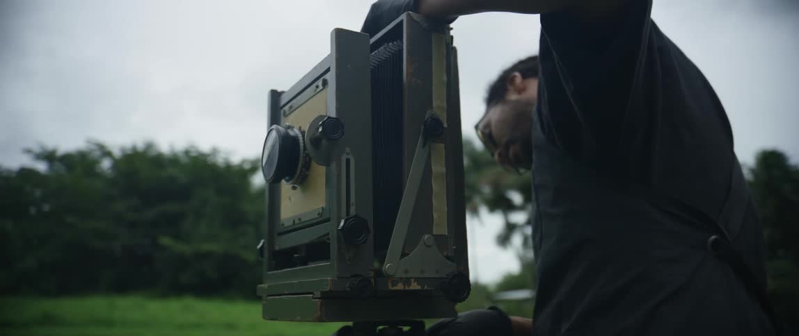 A man is setting up a film camera outdoors