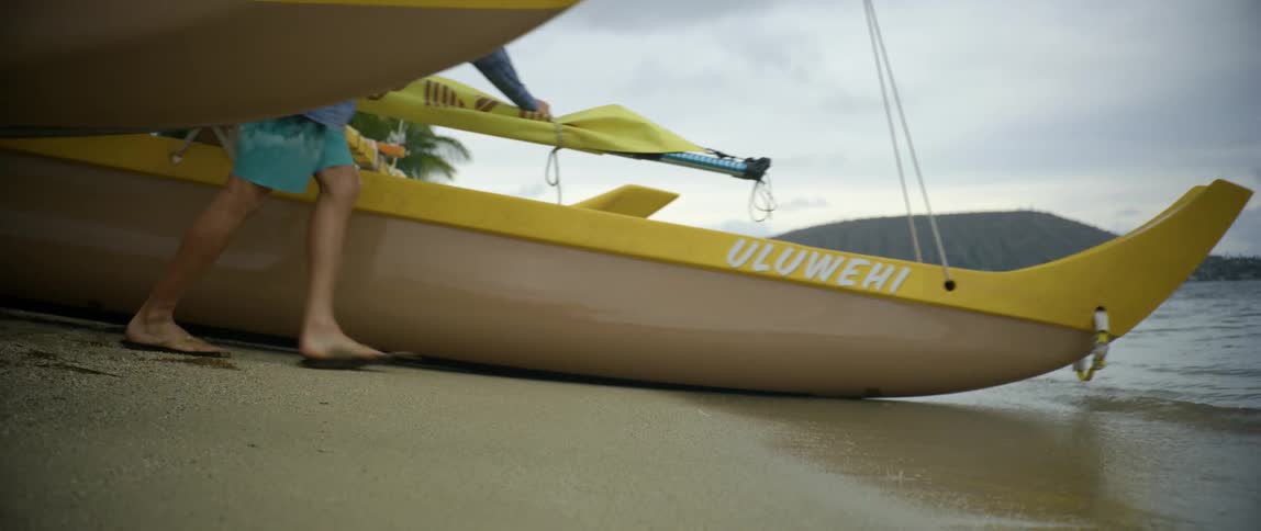A man pushes a boat off of the shore and into the water