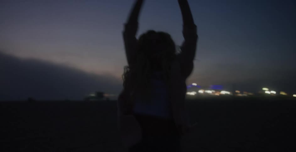 Woman runs toward blurry town lights at night