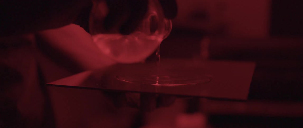 Clear liquid is poured from a beaker onto a square tile