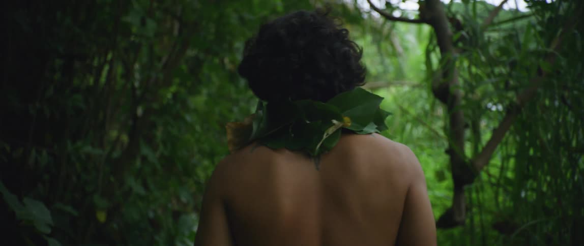 A shirtless man is traveling through the forest
