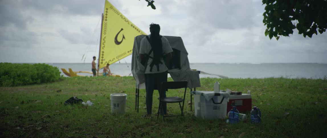 A man stands in front of a display outdoors with supplies and a water cooler at daytime