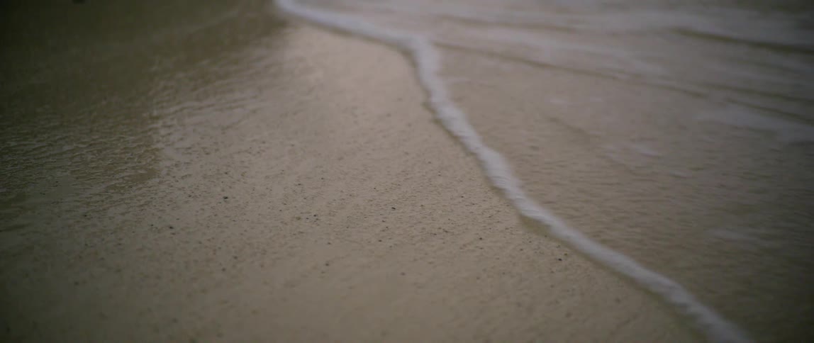Waves washing over the sand on a beach at sunset