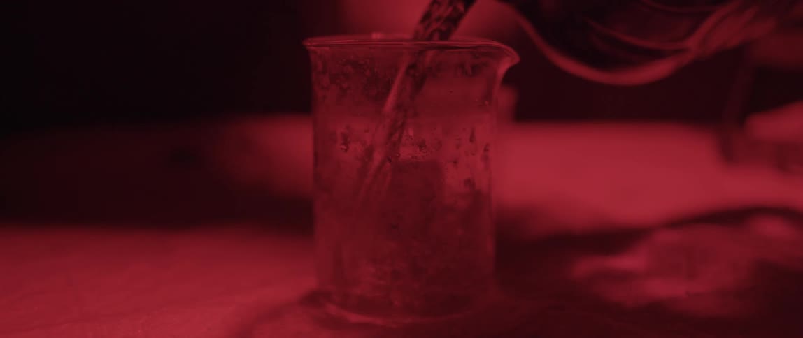 A liquid being poured into a container with red light