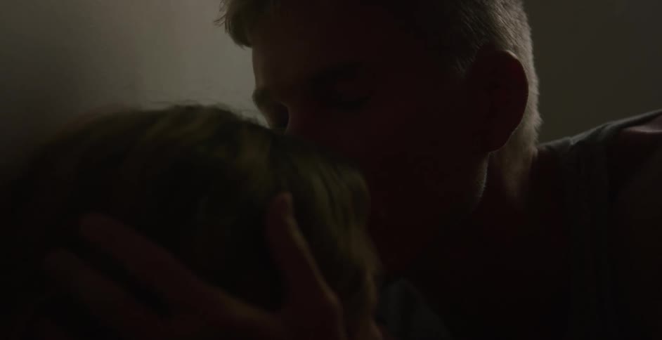 A man talks with a woman and then takes her head in his hands and kisses her on the head