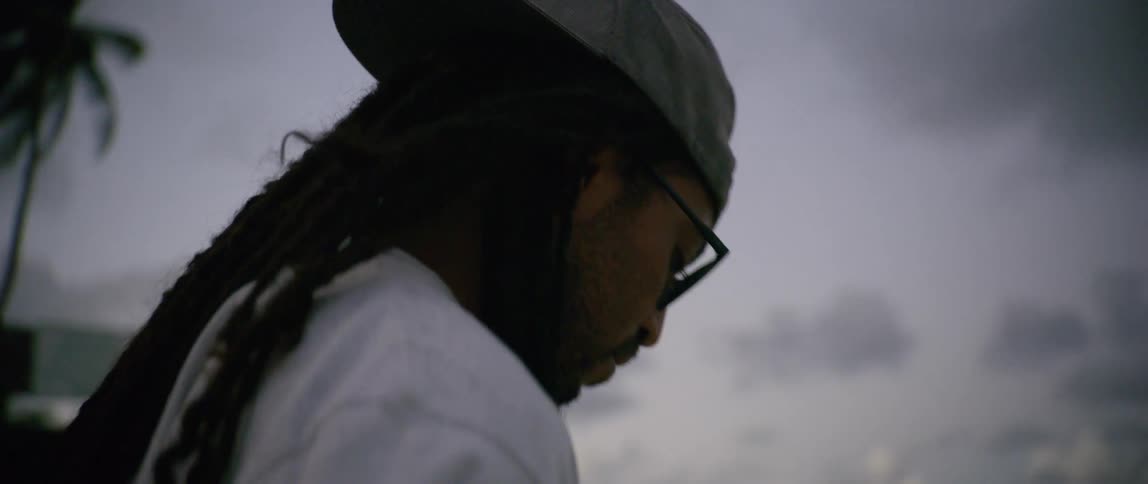 A man stands contemplatively outdoors on a cloudy day