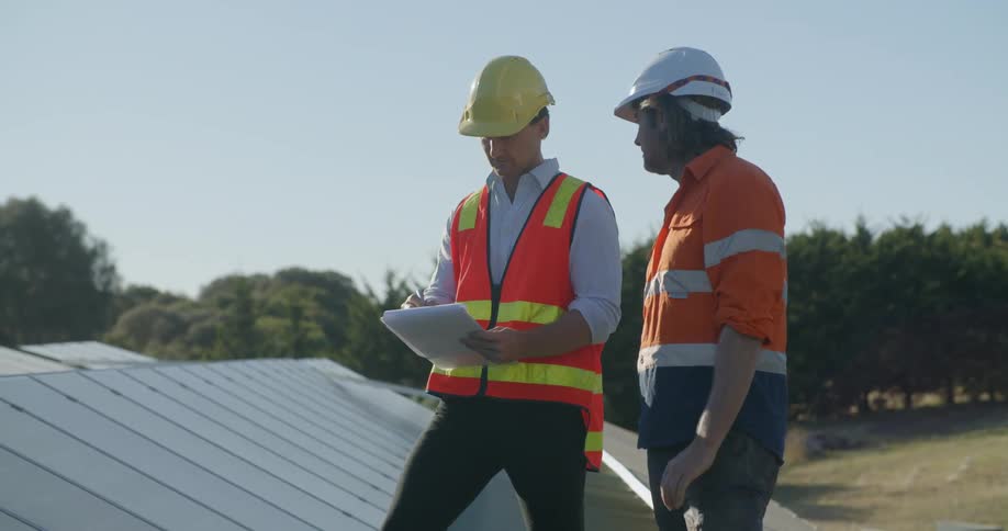 Two construction workers planning the instalation of solar panels in the roof of a building