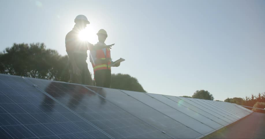 Two employees stand an talk as they look at solar panels