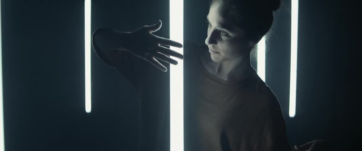 Woman posing around floating fluorescent bulbs in a dark room