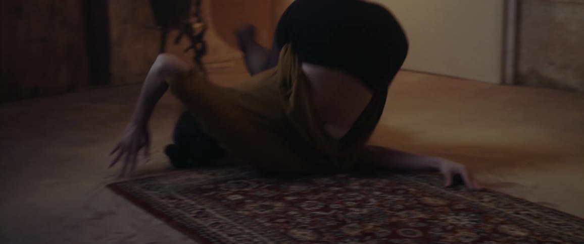 Woman practices dance moves on a mat in a room