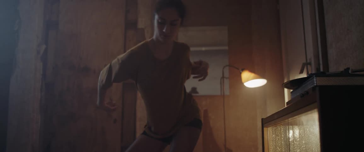 A woman dances with a broken plate on the floor next to her