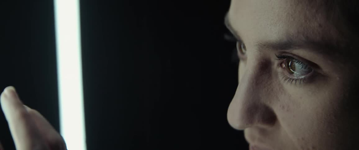 A close up of a womans face staring intently at a light