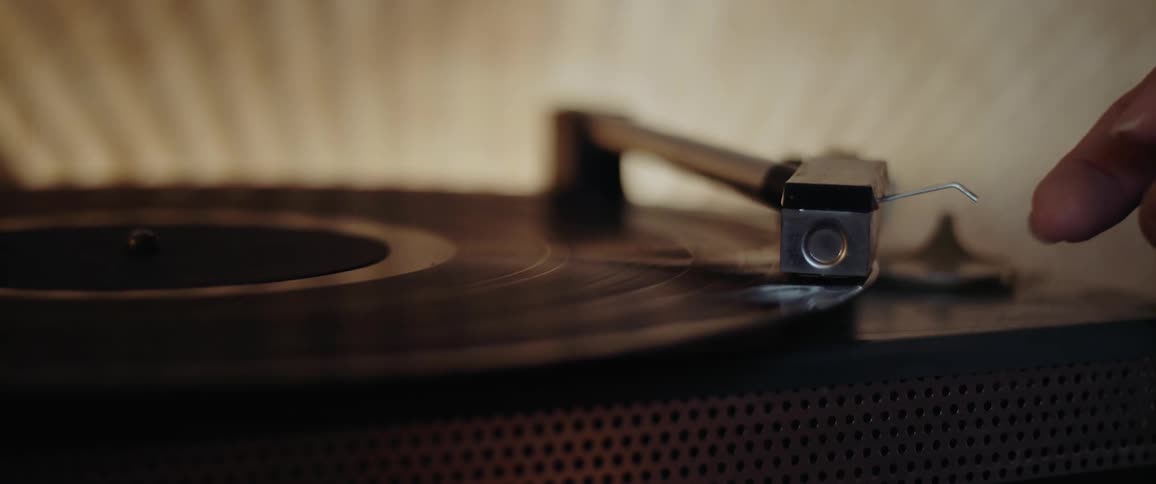 A person puts the record player needle down on an album