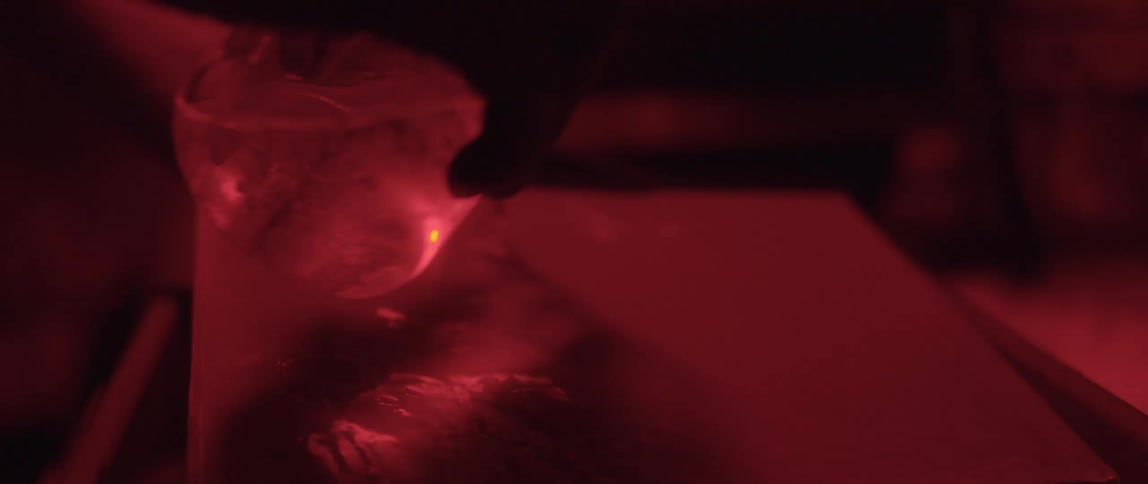 Photographer in a dark room uses liquids to develop a picture